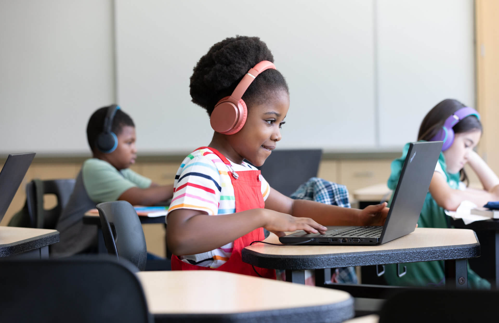 This is a decorative image showing a young girl using a laptop and headphones. 