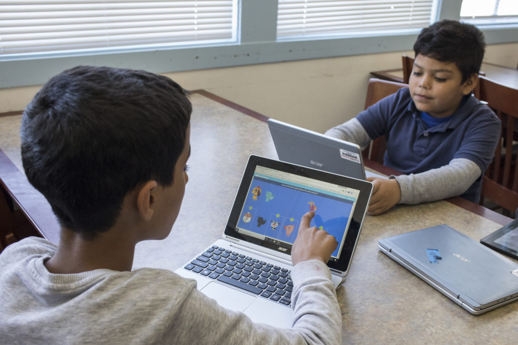 This is a photo image of two children using devices to engage in high-impact tutoring.