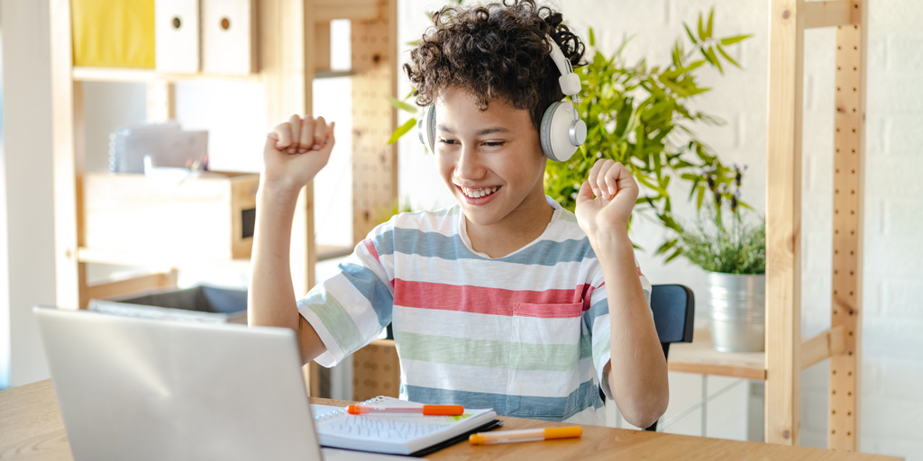 The image accompanying this article features a student engaged in virtual tutoring. he is seated in front of his computer, wearing headphones and looking focused. 